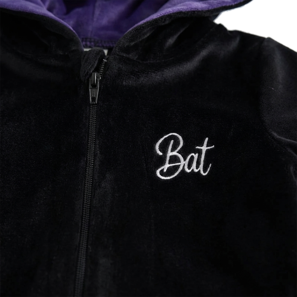 Close-up of the embroidered Bat script on the chest beside the full-length zipper with its covered pull